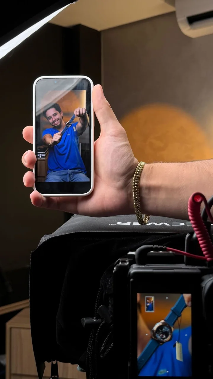 Celular mostrando a foto de um relógio sendo gravado, com a câmera e o monitor em primeiro plano